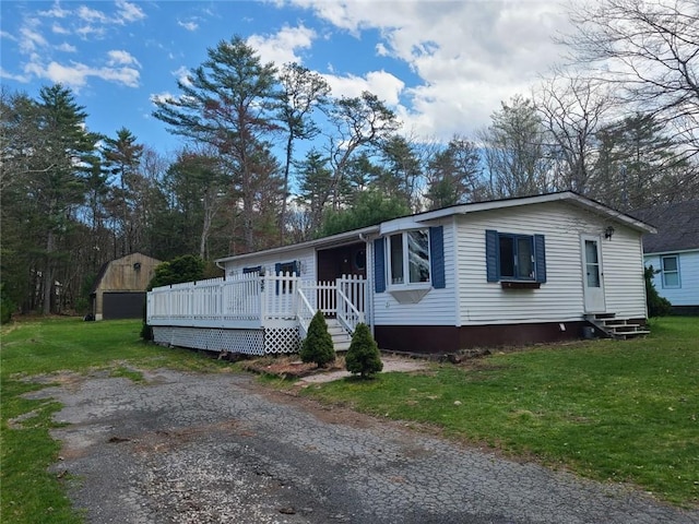 view of front of house with a storage shed, a deck, and a front lawn