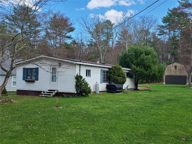 back of property featuring a yard and an outdoor structure