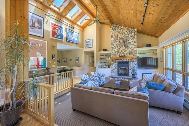 living room featuring a skylight, ceiling fan, high vaulted ceiling, wooden ceiling, and a fireplace