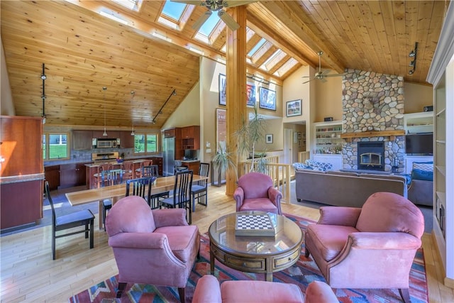 living room featuring a skylight, ceiling fan, beam ceiling, high vaulted ceiling, and light hardwood / wood-style floors