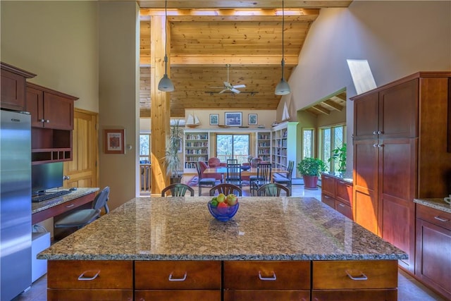 kitchen featuring beamed ceiling, a center island, high vaulted ceiling, and stainless steel refrigerator