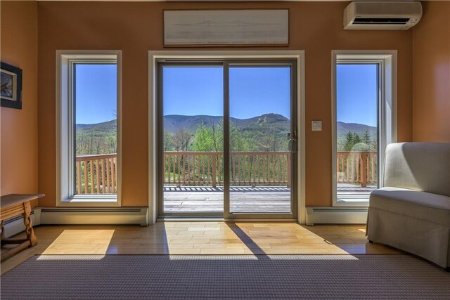 doorway to outside featuring a mountain view, a wall mounted air conditioner, and a baseboard heating unit