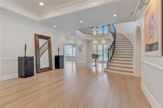 foyer featuring a tray ceiling, french doors, ornamental molding, and light wood-type flooring