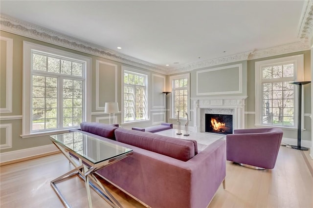 living room with light hardwood / wood-style flooring, a high end fireplace, a healthy amount of sunlight, and ornamental molding