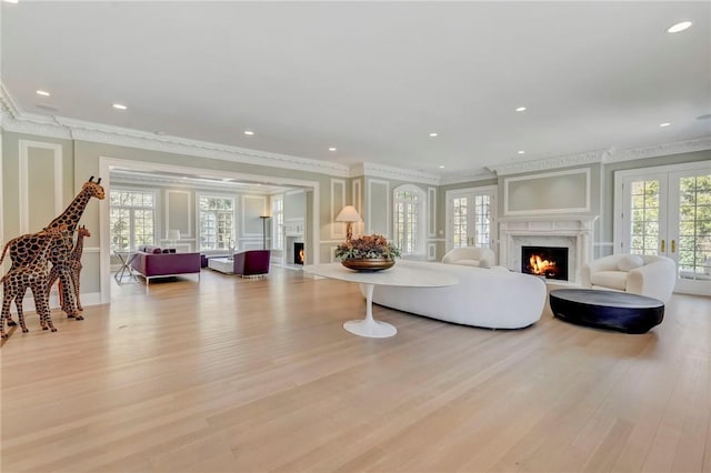 living room with french doors, crown molding, and light hardwood / wood-style flooring