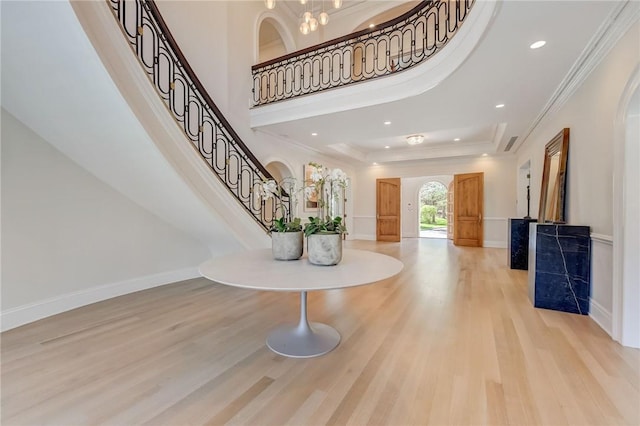 entryway featuring light hardwood / wood-style floors, a raised ceiling, and ornamental molding