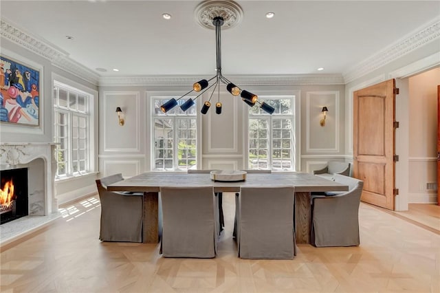 dining area with a premium fireplace, plenty of natural light, light parquet flooring, and crown molding