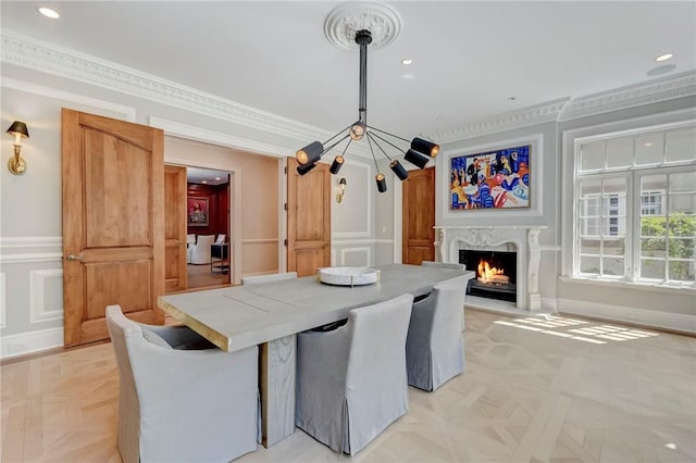 dining area featuring light parquet flooring, ornamental molding, and a premium fireplace