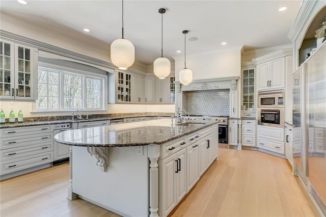 kitchen featuring dark stone countertops, white cabinets, an island with sink, and stainless steel appliances