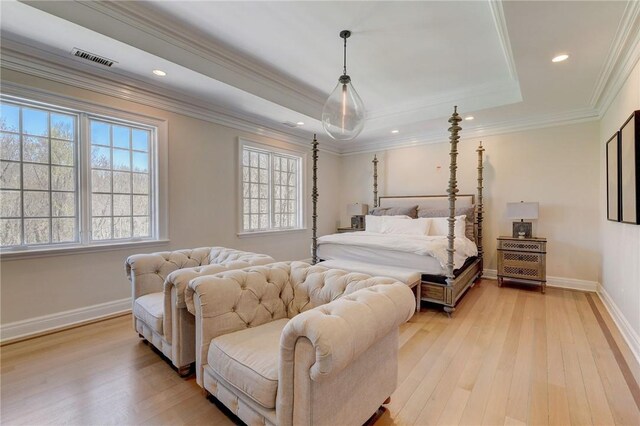 bedroom featuring light wood-type flooring, crown molding, and a tray ceiling