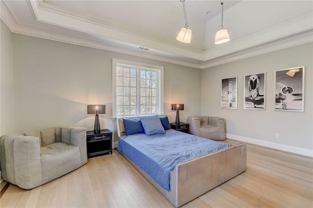 bedroom with light wood-type flooring, a raised ceiling, and ornamental molding