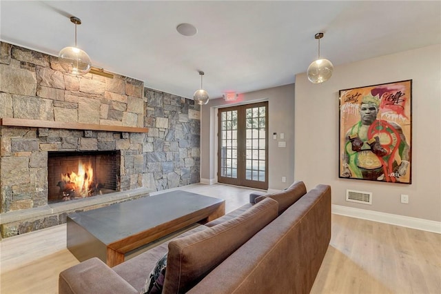 living room with french doors, a fireplace, and light hardwood / wood-style flooring