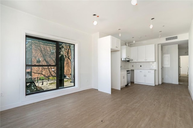 kitchen with backsplash, decorative light fixtures, light hardwood / wood-style flooring, dishwasher, and white cabinets