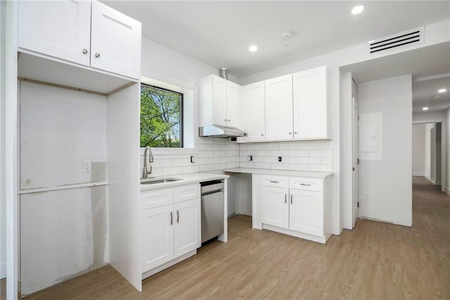 kitchen with white cabinetry, sink, stainless steel dishwasher, light hardwood / wood-style floors, and decorative backsplash