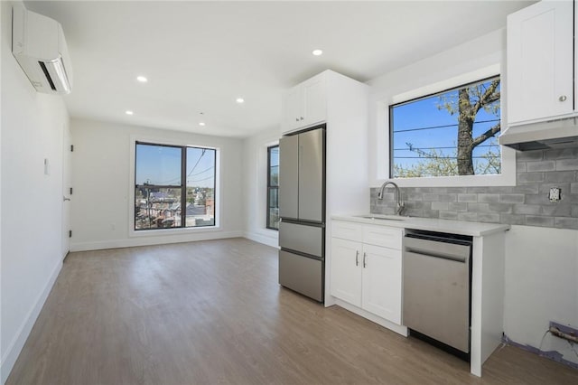 kitchen with white cabinetry, sink, tasteful backsplash, a wall mounted AC, and appliances with stainless steel finishes