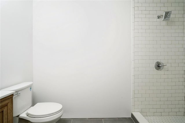 bathroom featuring tiled shower, tile patterned floors, vanity, and toilet