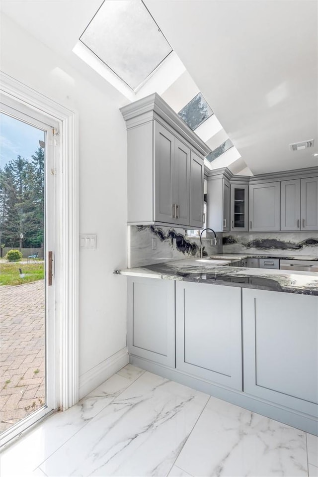 kitchen featuring gray cabinets, decorative backsplash, sink, and a healthy amount of sunlight