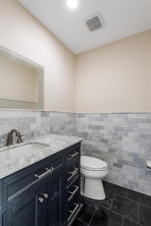 bathroom featuring tile patterned floors, vanity, tile walls, and toilet