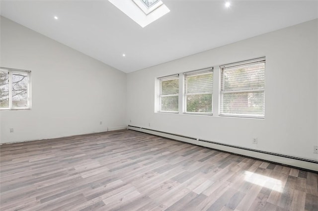 empty room featuring light wood-type flooring, a wealth of natural light, and a baseboard heating unit