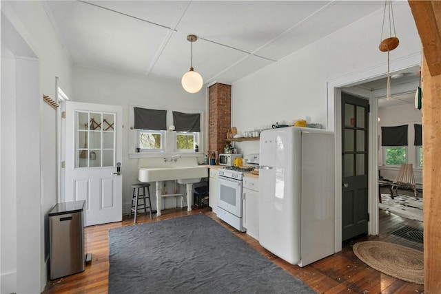 kitchen featuring pendant lighting, white appliances, and dark wood-type flooring