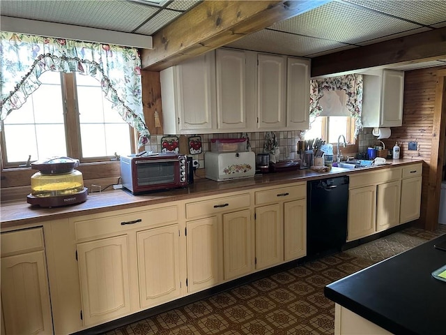 kitchen with dishwasher, wood walls, cream cabinets, sink, and tasteful backsplash