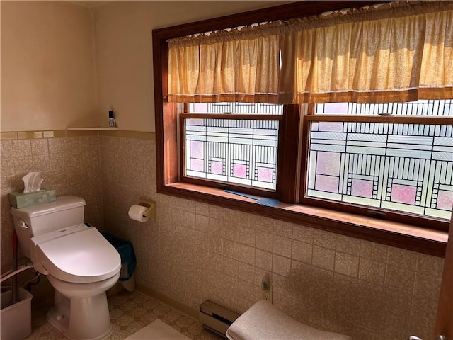 bathroom with a baseboard radiator, plenty of natural light, and tile walls