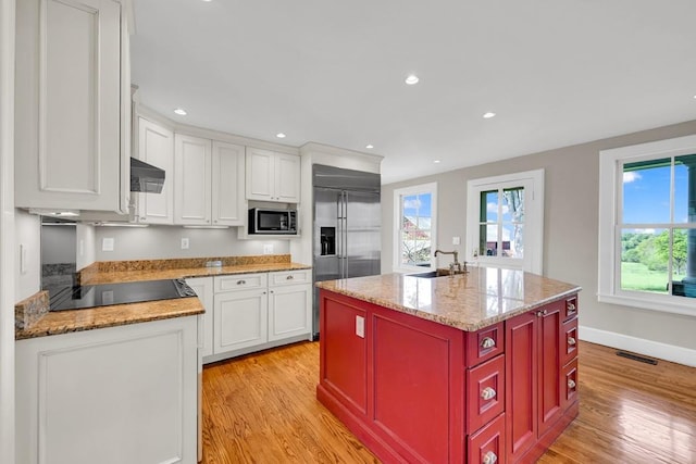 kitchen with white cabinets, an island with sink, and light hardwood / wood-style floors