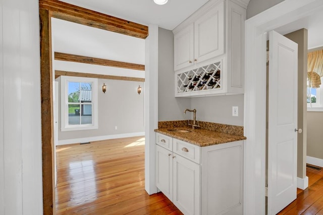 kitchen featuring stone countertops, light hardwood / wood-style floors, white cabinetry, and sink