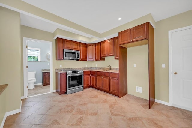 kitchen featuring light stone counters, sink, light tile patterned flooring, and stainless steel appliances