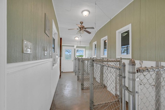 corridor featuring wood walls, concrete flooring, and vaulted ceiling