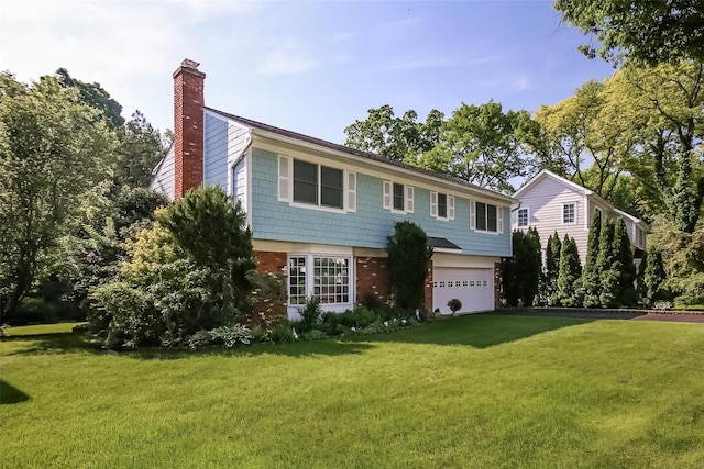 colonial home with a garage, a front yard, a chimney, and brick siding