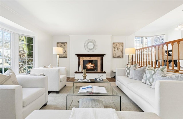 living room with a lit fireplace, crown molding, stairway, and wood finished floors