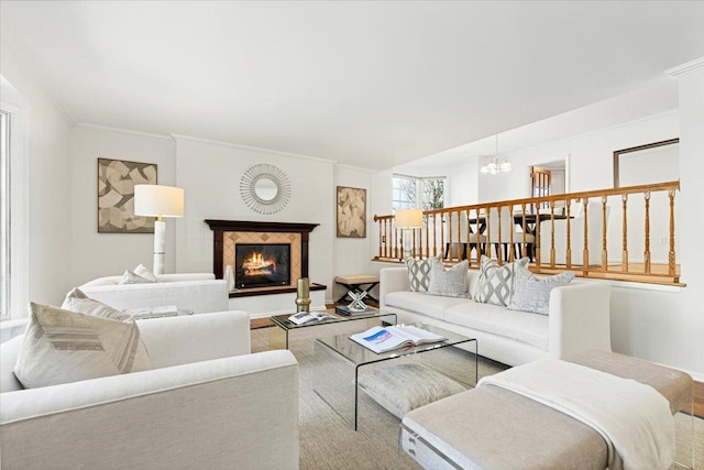 living area featuring ornamental molding, a notable chandelier, and a lit fireplace