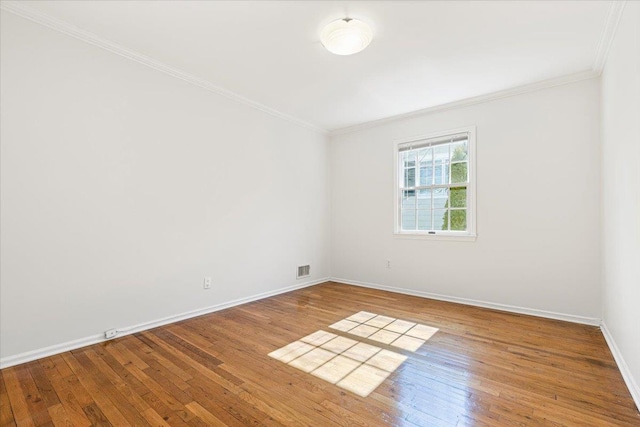 spare room featuring crown molding, baseboards, and hardwood / wood-style flooring