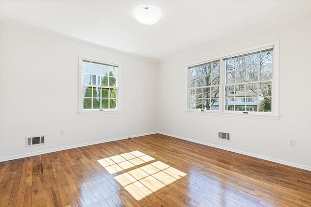 unfurnished room with wood-type flooring, visible vents, and crown molding