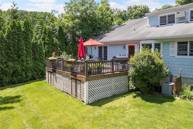 rear view of property with a shingled roof, a wall unit AC, a deck, a yard, and central AC