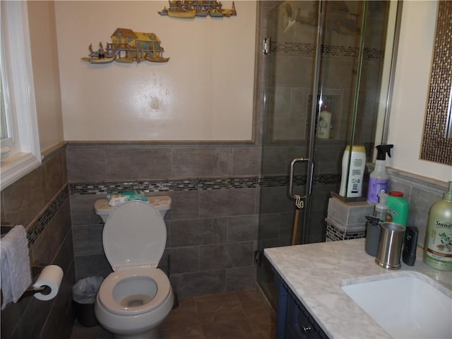 bathroom featuring vanity, toilet, walk in shower, and tile walls