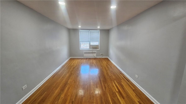 unfurnished room with hardwood / wood-style flooring, cooling unit, and radiator