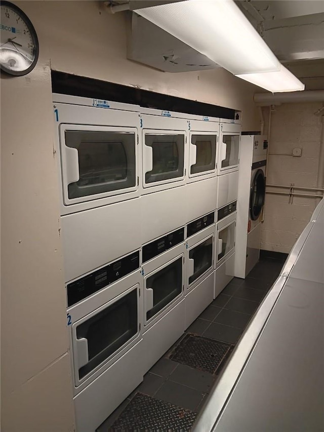 clothes washing area with washer and dryer, dark tile patterned floors, and stacked washer and clothes dryer