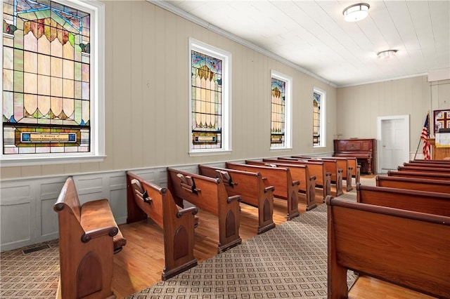 home theater with light wood-type flooring, wooden walls, and ornamental molding