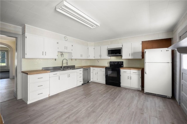 kitchen with appliances with stainless steel finishes, light wood-type flooring, tasteful backsplash, sink, and white cabinetry