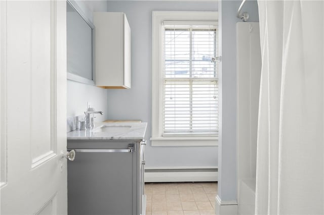 washroom featuring light tile patterned floors, baseboard heating, and sink