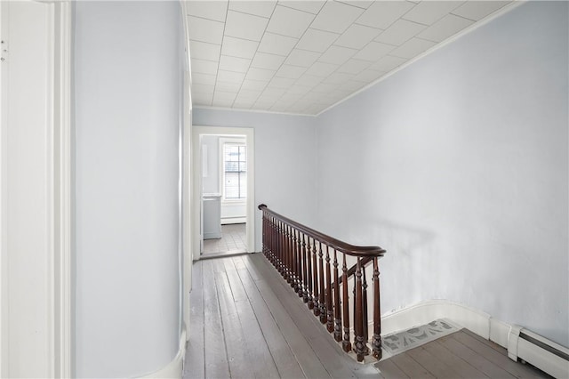 corridor with hardwood / wood-style floors, a baseboard radiator, and ornamental molding