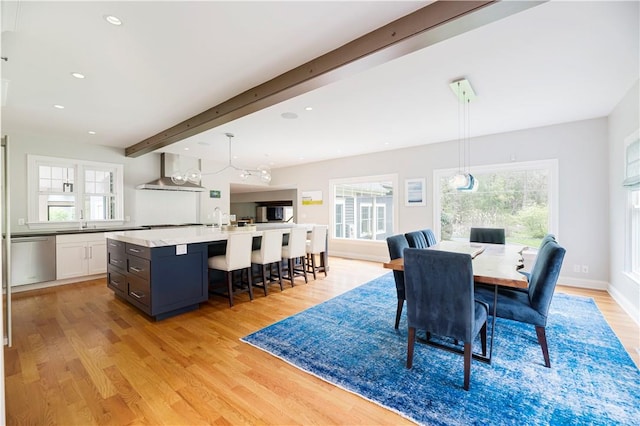 dining space featuring beamed ceiling, light hardwood / wood-style flooring, and sink