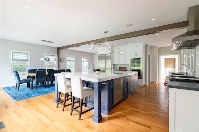 kitchen featuring beam ceiling, white cabinetry, sink, hanging light fixtures, and a spacious island