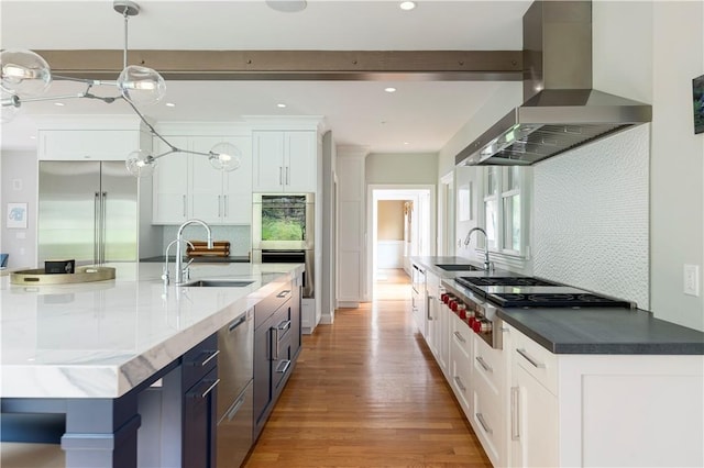 kitchen featuring wall chimney range hood, sink, appliances with stainless steel finishes, and light hardwood / wood-style flooring