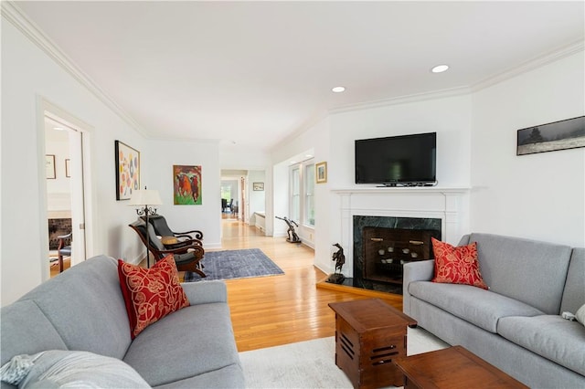 living room featuring ornamental molding, a high end fireplace, and light hardwood / wood-style flooring