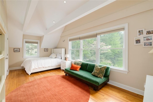 bedroom with hardwood / wood-style floors, lofted ceiling with beams, and multiple windows