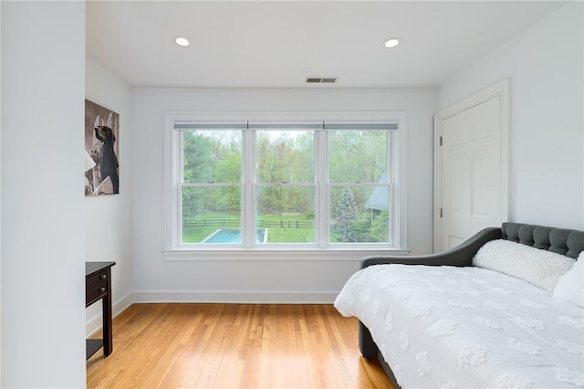 bedroom with multiple windows and light hardwood / wood-style flooring