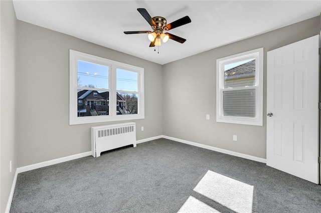 unfurnished bedroom featuring dark colored carpet, ceiling fan, and radiator heating unit